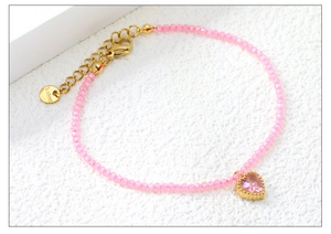 Dettaglio del ciondolo a cuore rosa e bracciale con perline e chiusura a moschettone dorata