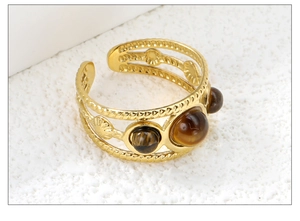 Close-up of golden multi-layer open ring with shell relief and three tiger eye stones