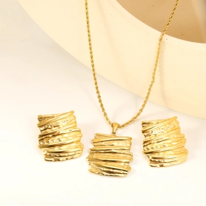 Golden jewelry set with textured wave pendant necklace and earrings on ceramic tray