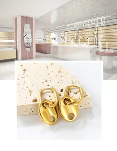 Détail de boucles d'oreilles en acier inoxydable doré sur un socle en pierre beige