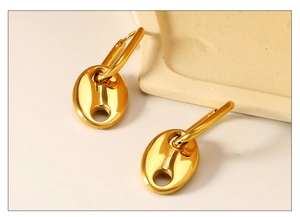 Détail de boucles d'oreilles grain de café dorées avec finition miroir polie brillante