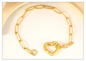 Detailed close-up of a minimalist 18K gold-plated heart clasp link bracelet on white stone