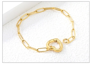 Detail shot of golden paperclip chain bracelet with a large heart-shaped clasp closure