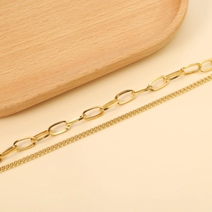 Detail of 18K gold heart bracelet featuring paperclip link and classic twisted chain