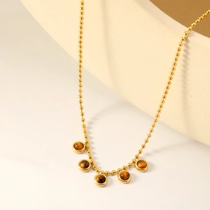 Collana con perline in oro 18 carati e cinque ciondoli occhio di tigre su supporto crema