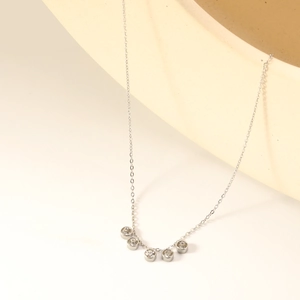 Elegante collana in argento con sei zirconi tondi curvi su un supporto crema minimalista