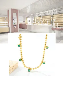 Close-up of golden beaded necklace with five emerald green crystal drop pendants