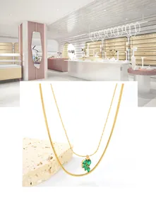 Close-up of double-layered gold necklace with green zircon leaf pendant on stone