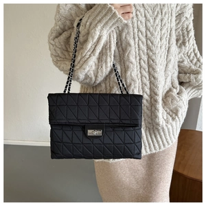 Large capacity black quilted chain shoulder bag worn by model in casual chic outfit