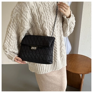 Detail of black quilted crossbody bag showing silver twist lock and chain strap texture