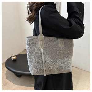 Detail of grey faux shearling tote bag featuring soft plush texture and leather straps
