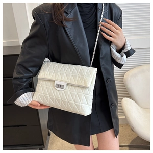 Detailed view of white quilted crossbody bag with silver chain strap and metal lock