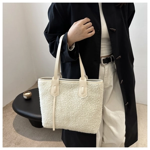 Détail du sac fourre-tout en peau de mouton beige avec anses cuir sur un mannequin en noir