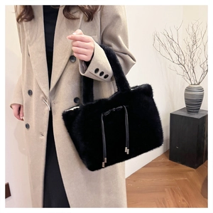 Dettaglio della borsa a mano in peluche nera con coulisse su cappotto di lana beige