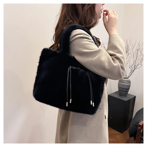 Dettaglio della borsa tote in ecopelliccia nera con texture morbida e chiusura a coulisse da donna