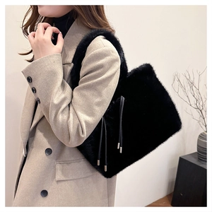 Dettaglio borsa tote in ecopelliccia nera con lacci e finiture dorate per outfit invernali