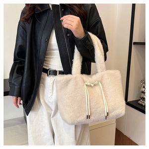 Dettaglio della borsa tote in pelliccia sintetica con lacci decorativi color crema