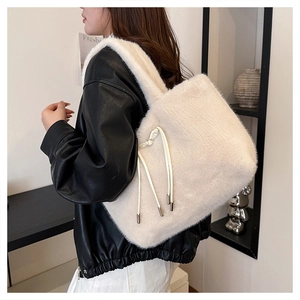 Dettaglio della borsa tote in ecopelliccia crema con coulisse e ciondolo in metallo lucido