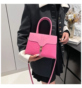 Detail of pink croc-embossed leather handbag with gold rectangular clasp and top handle