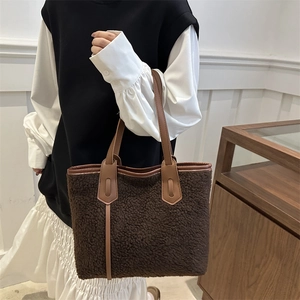 Sac fourre-tout en polaire marron avec bordure en cuir tenu par un mannequin élégant