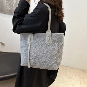 Sac cabas en polaire sherpa grise avec anses en cuir, porté à l'épaule sur manteau