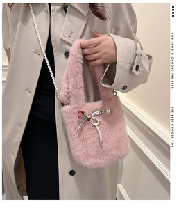 Détail du sac seau en fausse fourrure rose avec nœud en soie et chaîne de perles