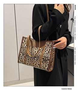 Détail du sac cabas léopard avec anses en cuir marron porté avec un blazer noir