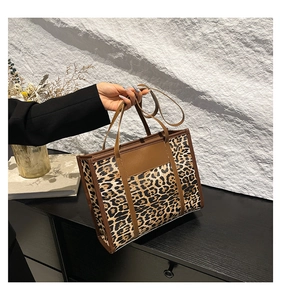 Détail du sac cabas léopard avec poignées en cuir marron et bandoulière réglable