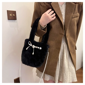 Sac à main en fausse fourrure avec chaîne en perles et nœud porté par un mannequin