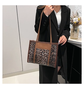 Sac fourre-tout chic à imprimé léopard avec lanières en cuir porté par un mannequin