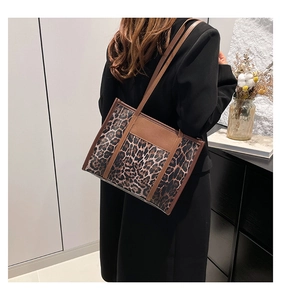 Chic leopard print tote bag with brown leather handles worn with a black blazer