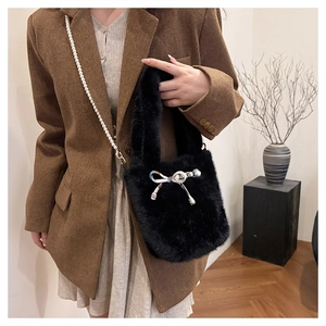 Détail du sac seau noir en fausse fourrure avec nœud blanc et bandoulière en perles