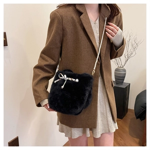 Détail du sac à main en fausse fourrure noire avec bandoulière perle et nœud en soie
