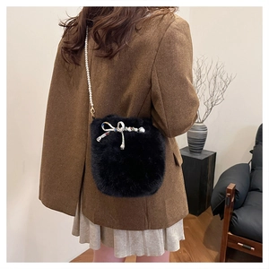 Détail du sac seau noir en fausse fourrure avec bandoulière perles et nœud décoratif