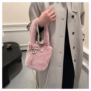 Détail d'un sac seau rose en fausse fourrure avec nœud argenté et bandoulière en perles