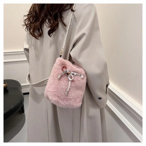 Gros plan du sac seau rose en fausse fourrure avec nœud perlé et bandoulière en perles