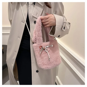Détail d'un sac seau en fausse fourrure rose avec nœud ruban et bandoulière perle