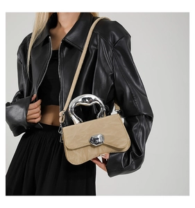 Detail of khaki crossbody bag featuring liquid silver metal handle and pebble twist lock