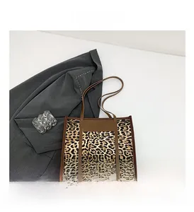Detail view of the leopard print tote bag with brown leather handles and sturdy stitching