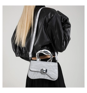 Detail of silver metallic wrinkled texture and liquid metal handle on cross-body bag