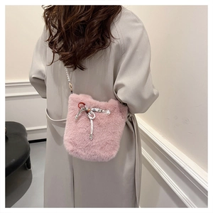 Détail du sac seau en fausse fourrure rose avec bandoulière perle et décoration nœud