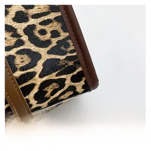 Close-up of leopard print fabric with brown leather reinforced stitching details