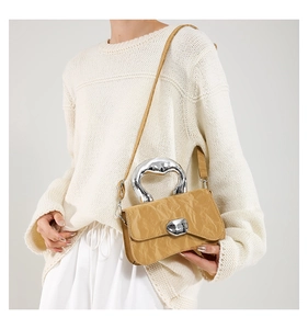 Detail of khaki pleated handbag featuring irregular silver metal handle and buckle