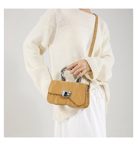 Close-up of yellow textured leather handbag with unique silver handle and metal buckle