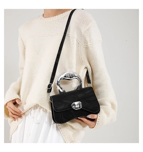 Detail of black handbag with lava-like silver metal handle and wrinkled texture on leather