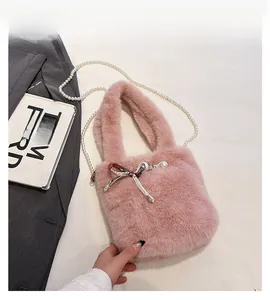 Détail du sac à main en fausse fourrure rose avec nœud, bouton perle et chaîne perlée
