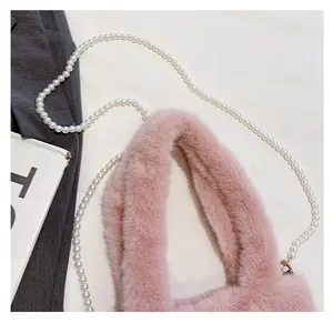 Détail du sac seau en fausse fourrure rose avec bandoulière décorative en perles chic
