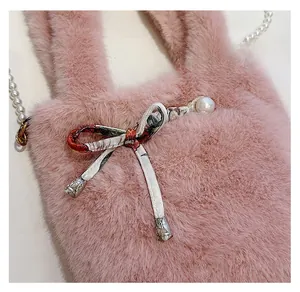 Détail du sac en fausse fourrure rose avec bandoulière perle, nœud floral et breloques