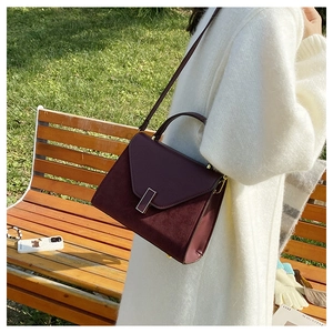 Detail of burgundy frosted Kelly bag featuring metal vertical clasp and top handle