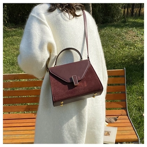 Chic burgundy leather crossbody bag with suede stitching on a stylish white knit sweater